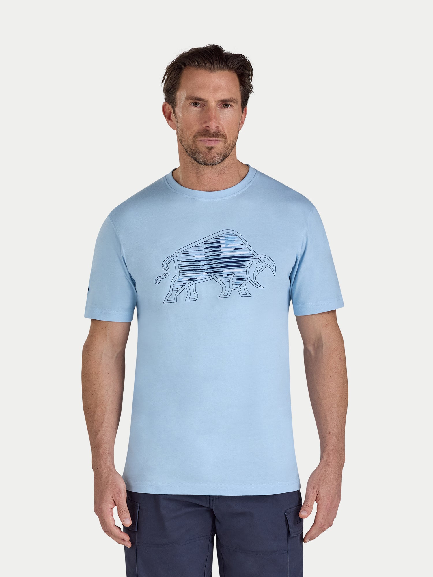 Man wearing a light blue t-shirt with a graphic design on a white background