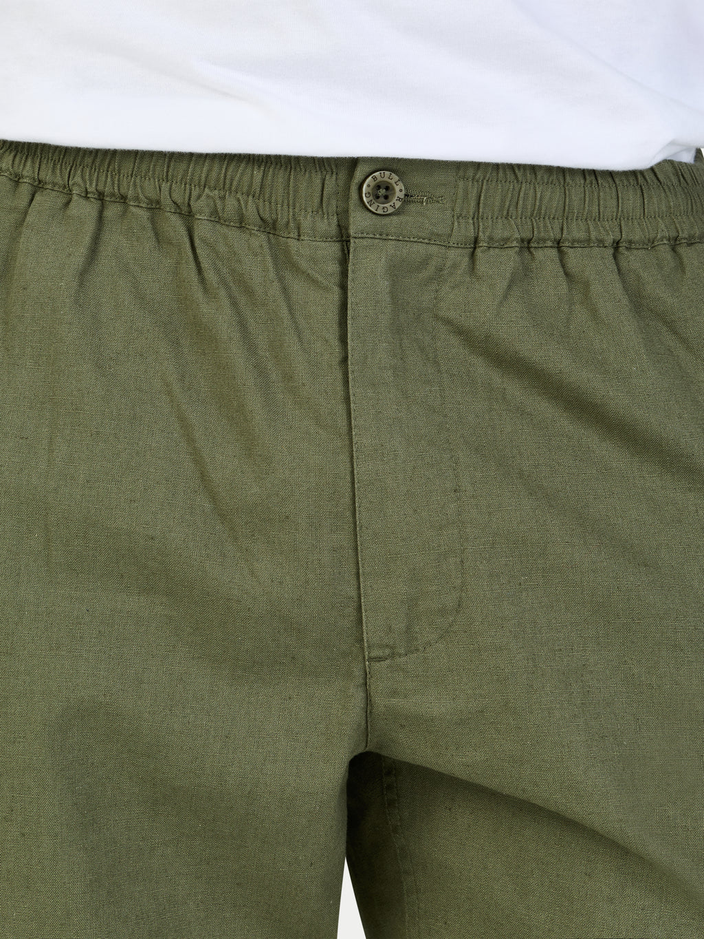 Close-up of green shorts with an elastic waistband and button on a white background