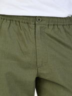 Close-up of green shorts with an elastic waistband and button on a white background