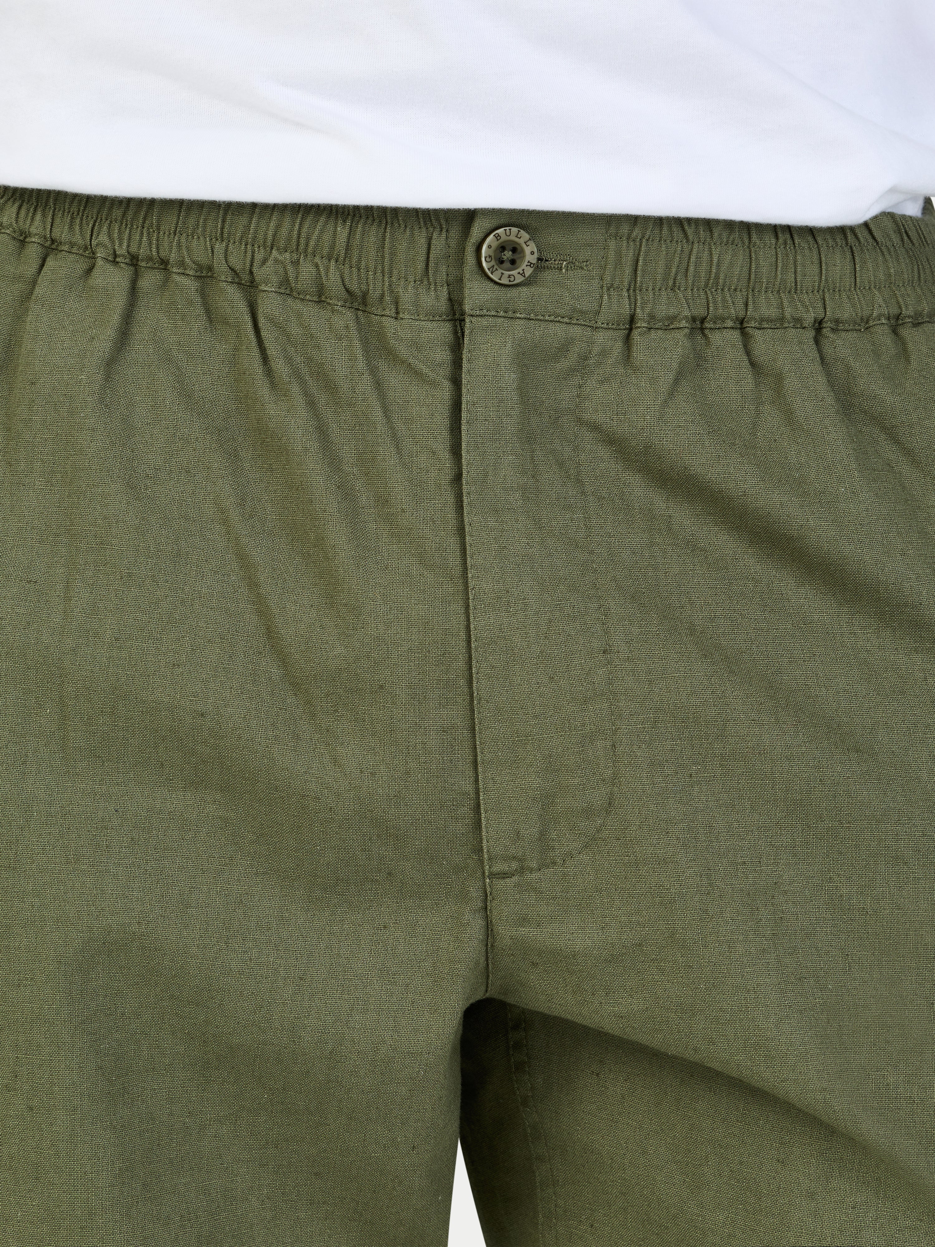 Close-up of green shorts with an elastic waistband and button on a white background