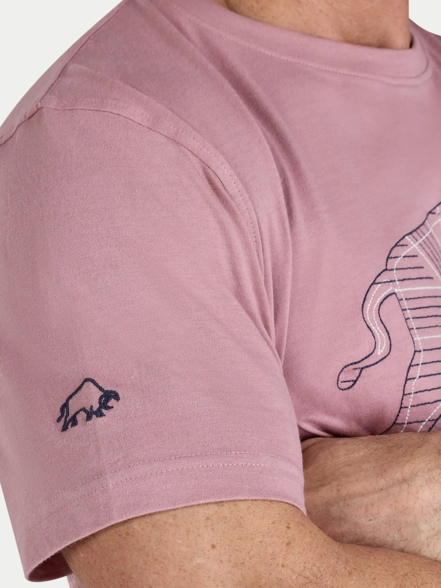 Close-up of a pink t-shirt with a logo on the sleeve and design on the chest.