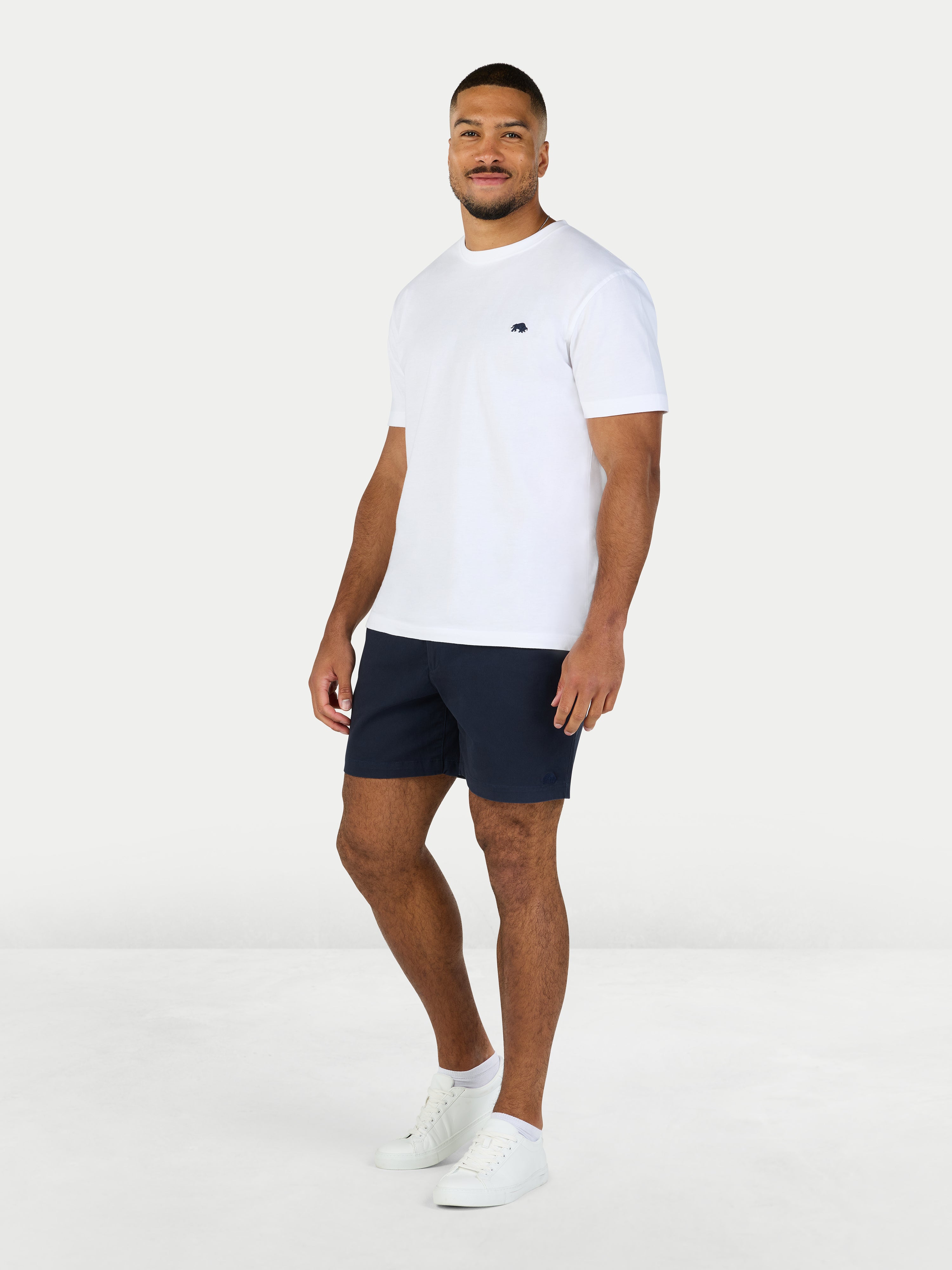 Man wearing a white t-shirt and navy shorts on a white background