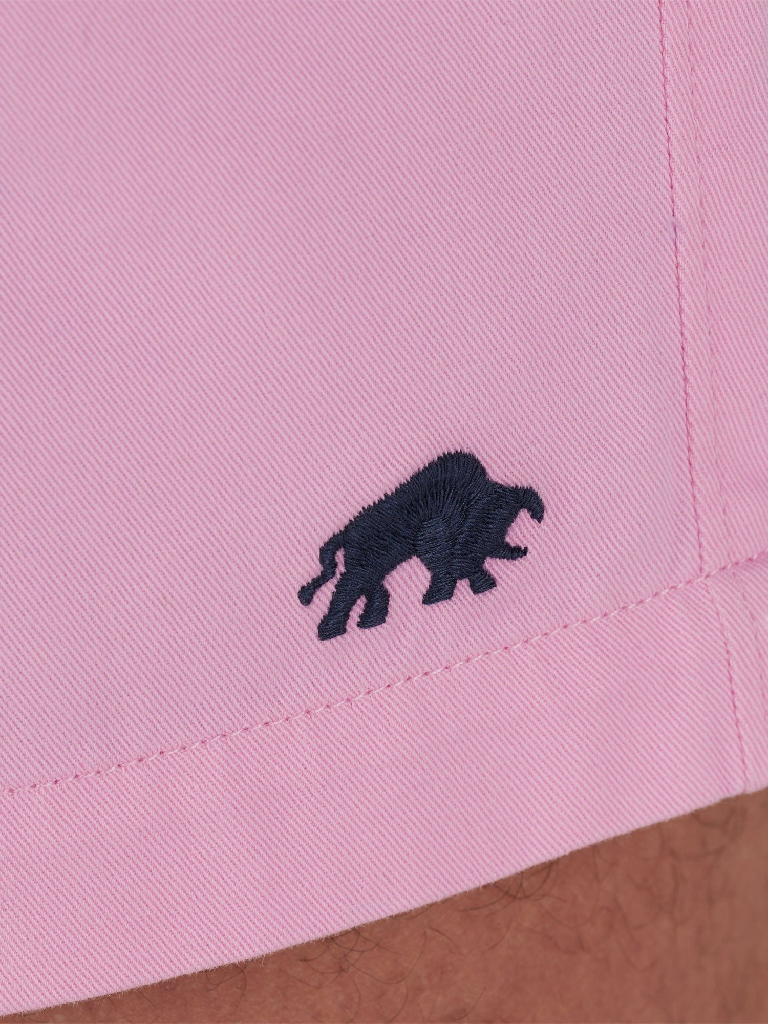 Close-up on the pink fabric of the shorts and a Raging bull logo. 
