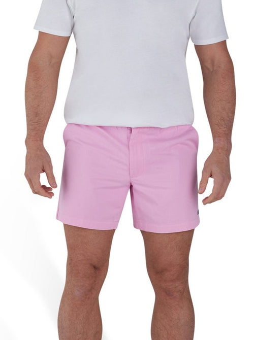 Man wearing a white t-shirt and stretch chino short in pink. 