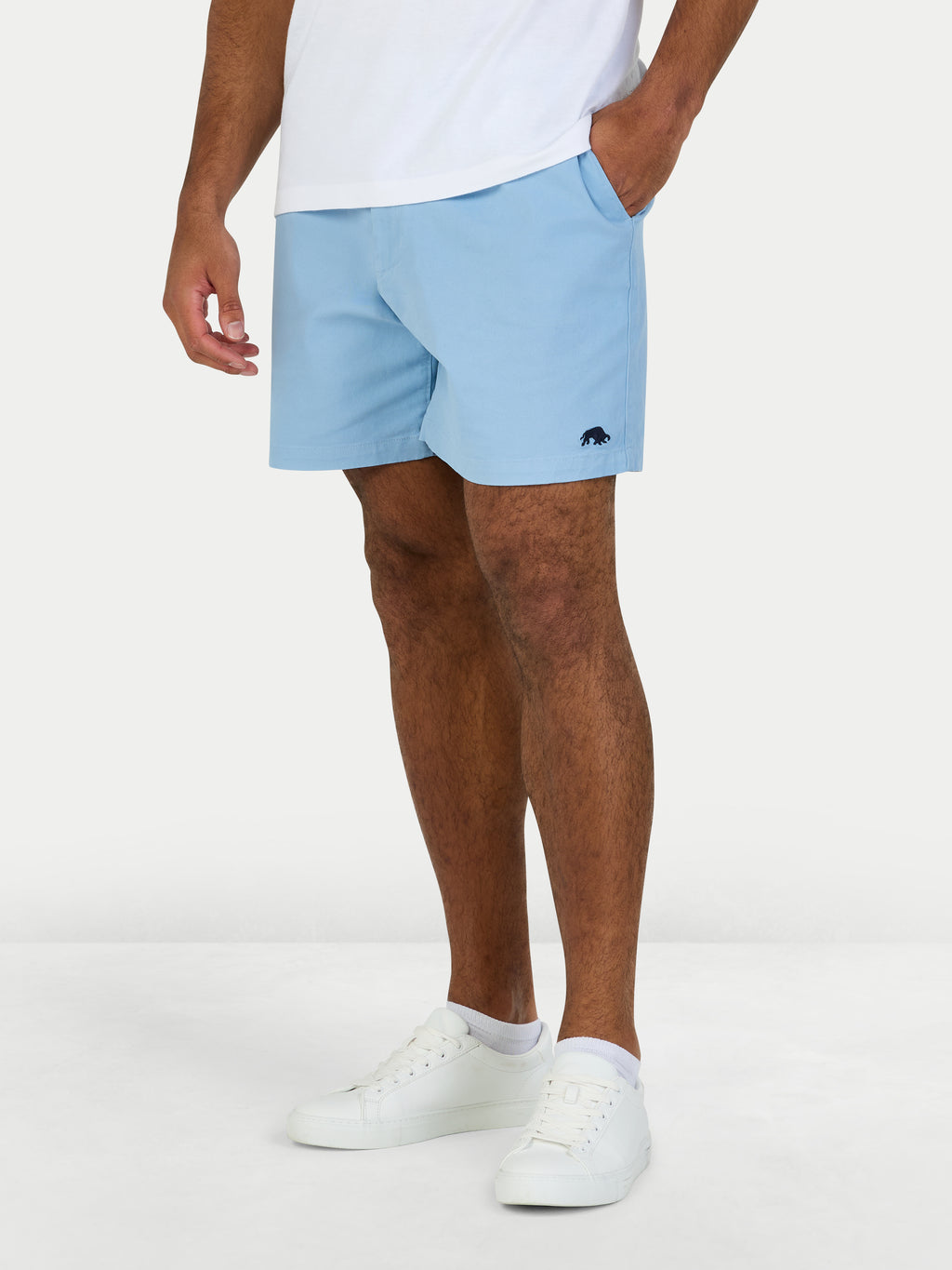 Person wearing light blue shorts and white sneakers on a white background