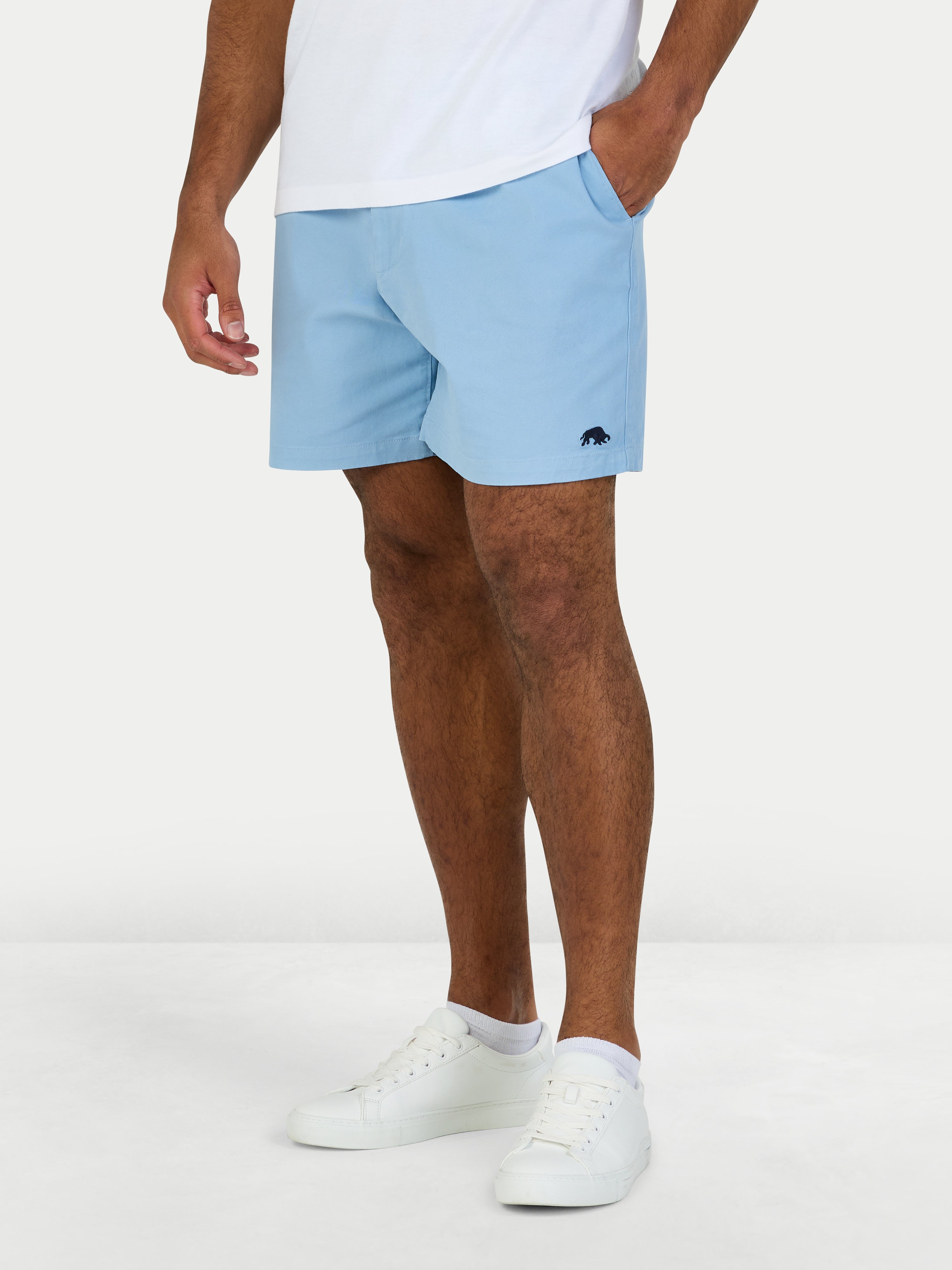 Person wearing light blue shorts and white sneakers on a white background