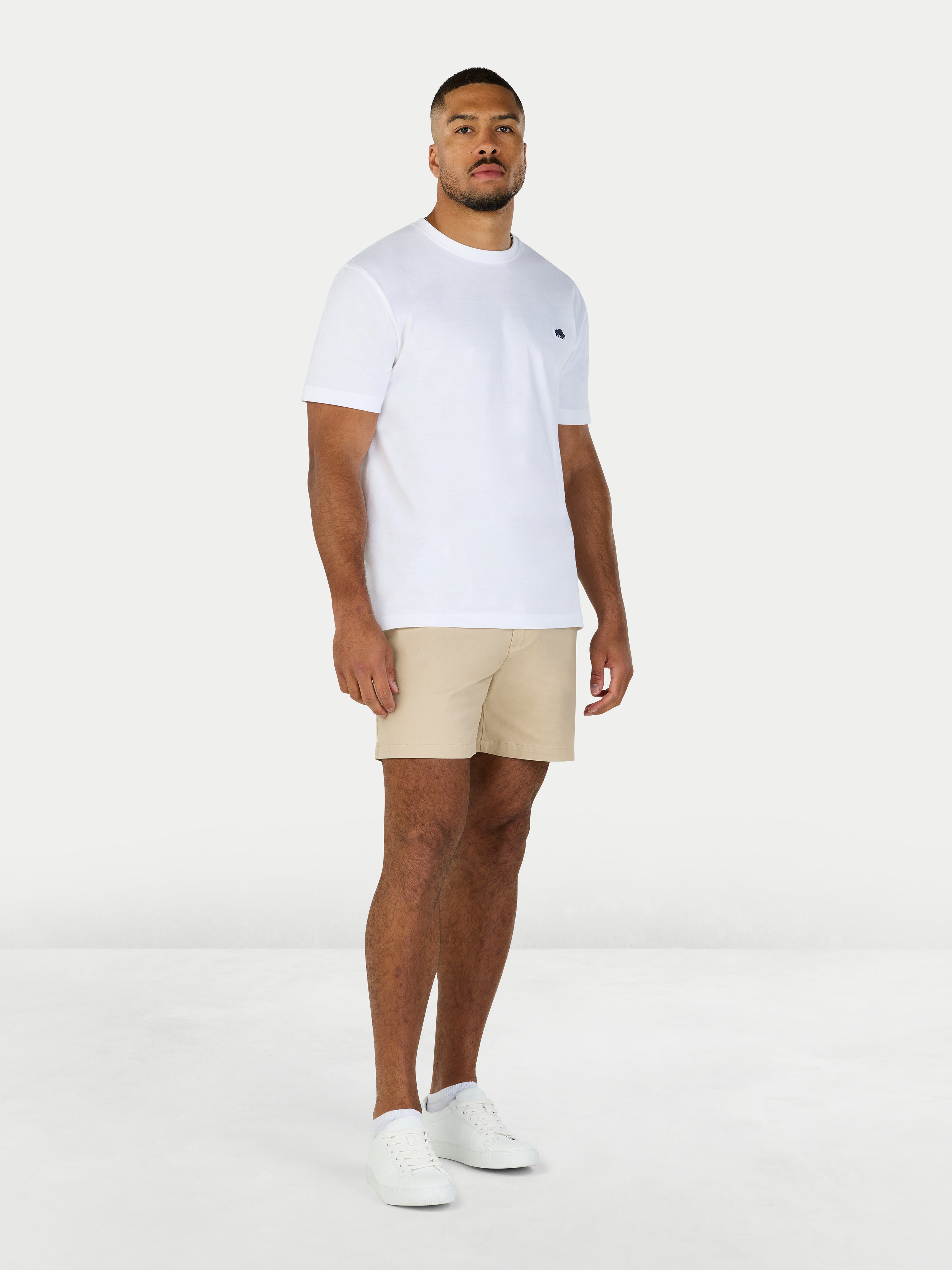 Man wearing a white t-shirt and beige shorts on a white background