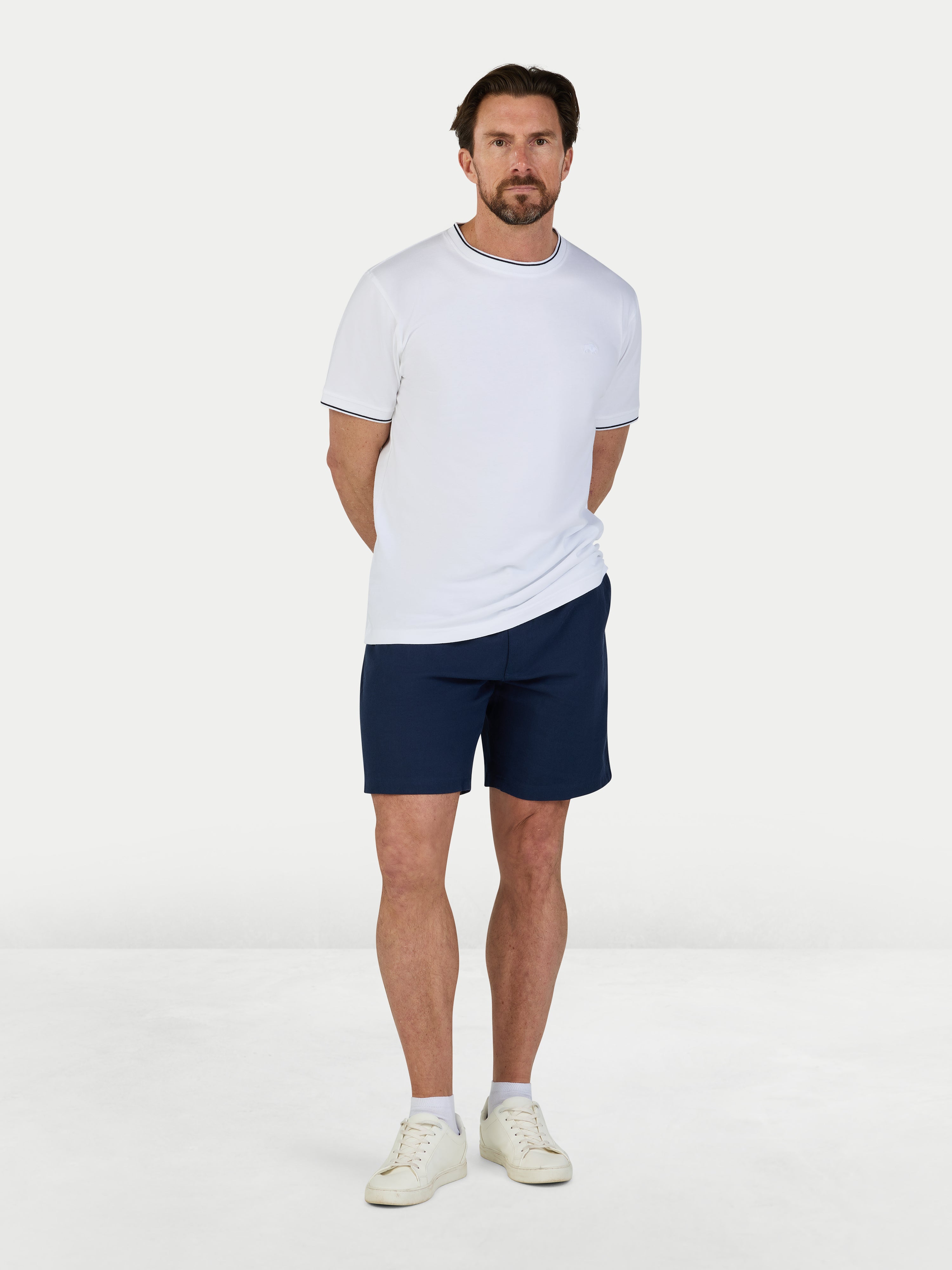 Man wearing a white t-shirt and navy shorts on a white background