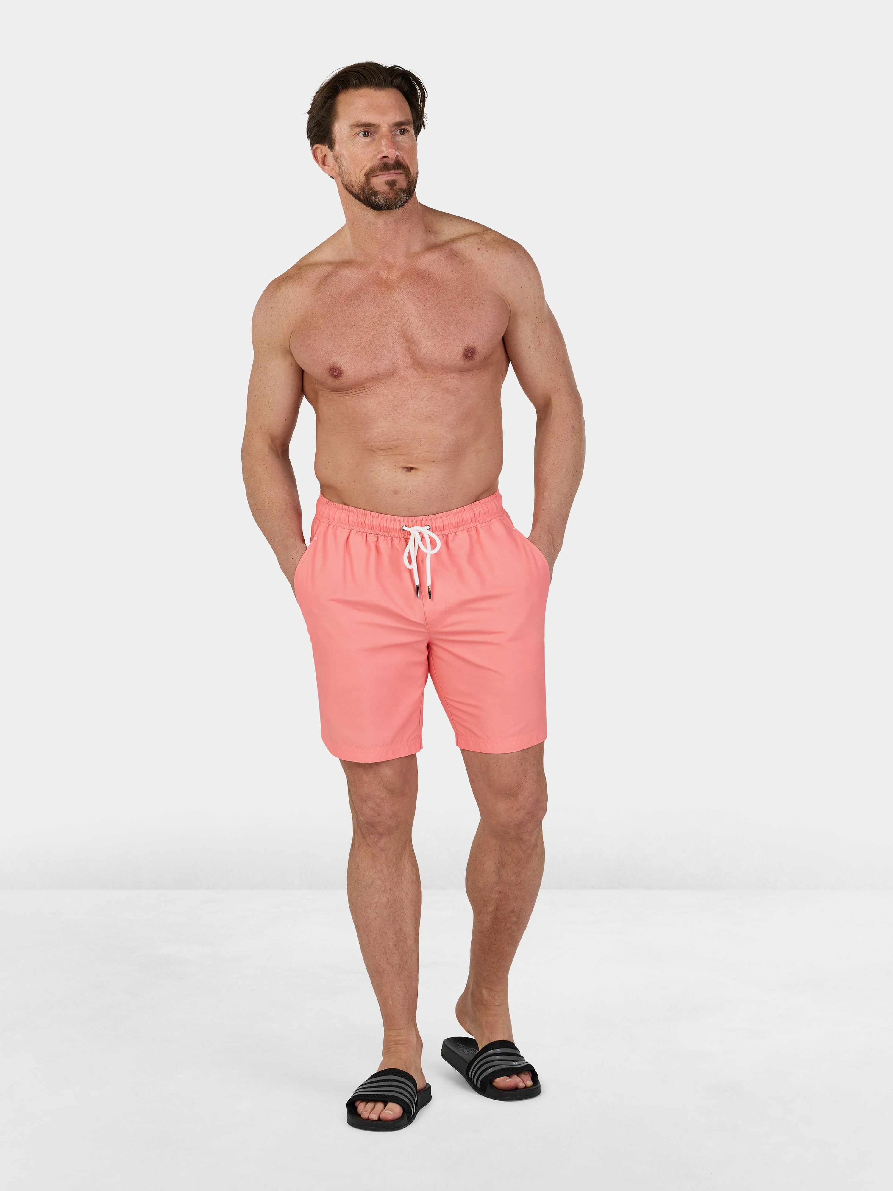 Man wearing pink swim shorts on a white background