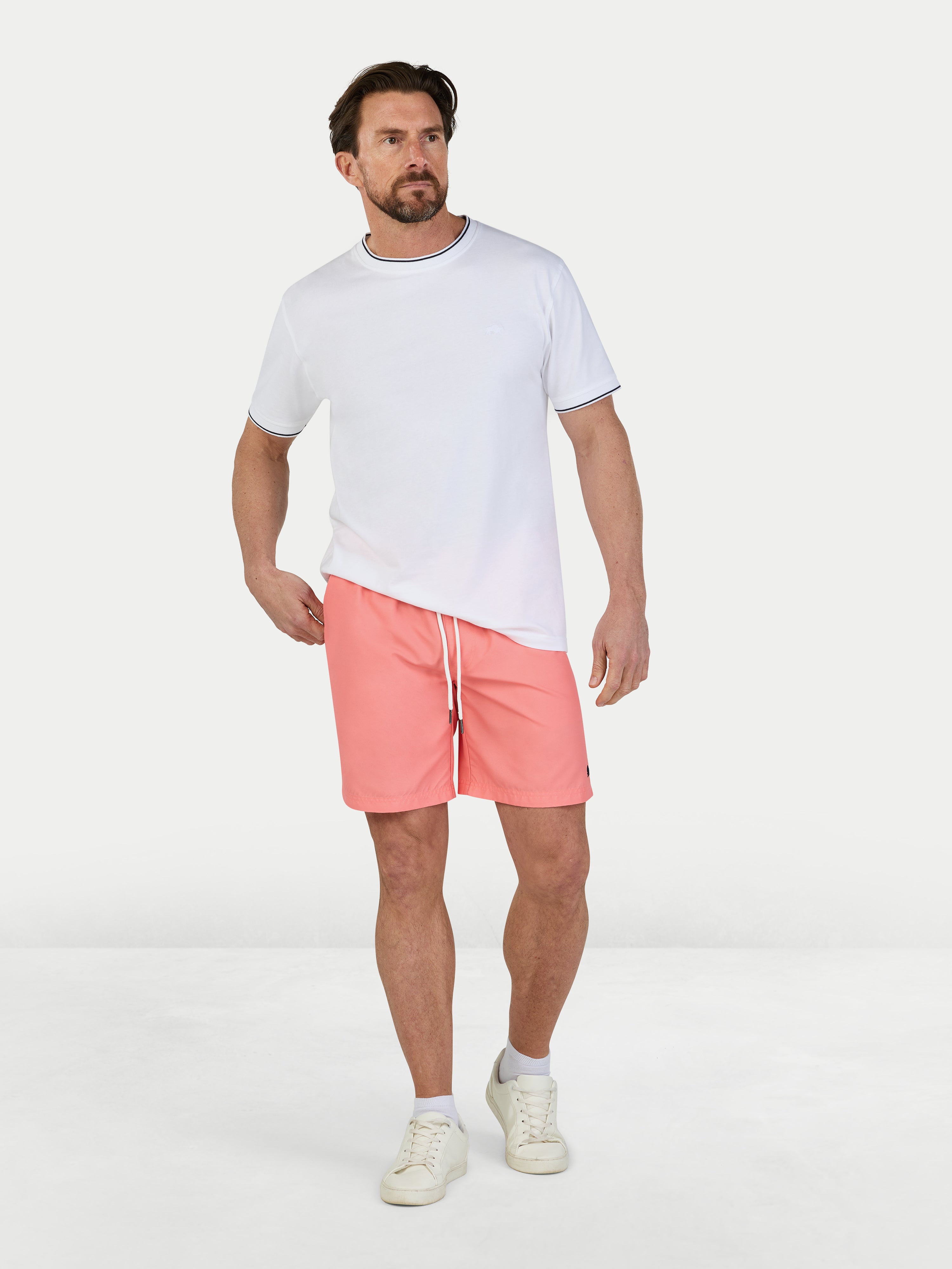 Man wearing a white t-shirt and pink shorts on a white background
