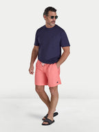 Man wearing Raging Bull Swim Shorts - Coral and t-shirt in navy, front. 