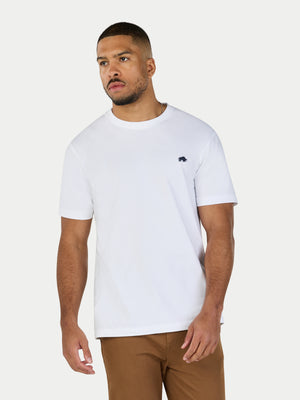 Man wearing a white t-shirt with a small logo on a plain background