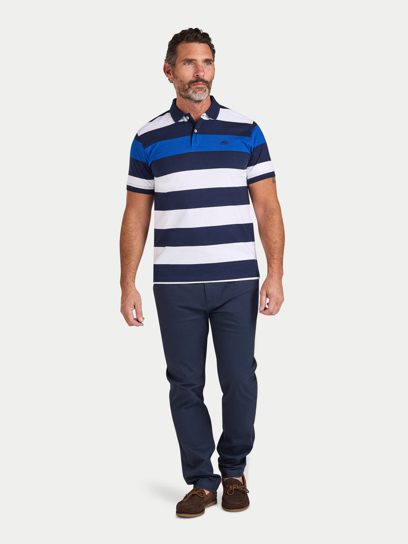 Man wearing a blue and white striped polo shirt with navy pants on a white background