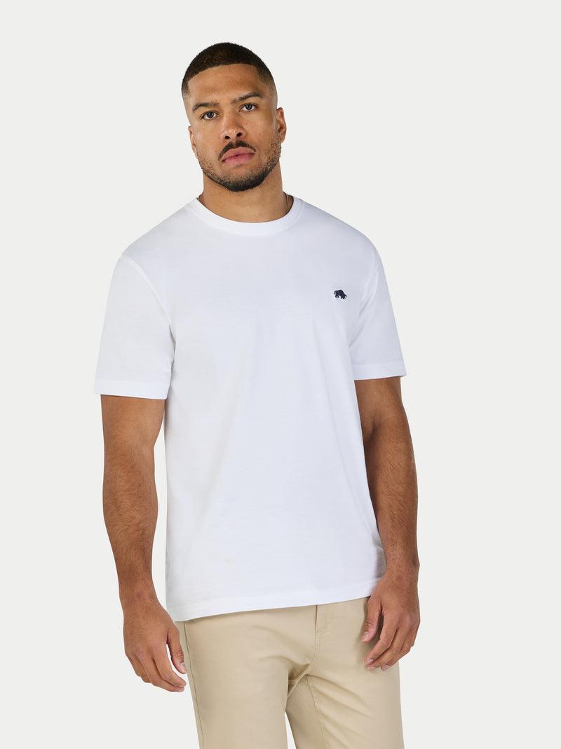 Man wearing a white t-shirt with a small logo on a white background