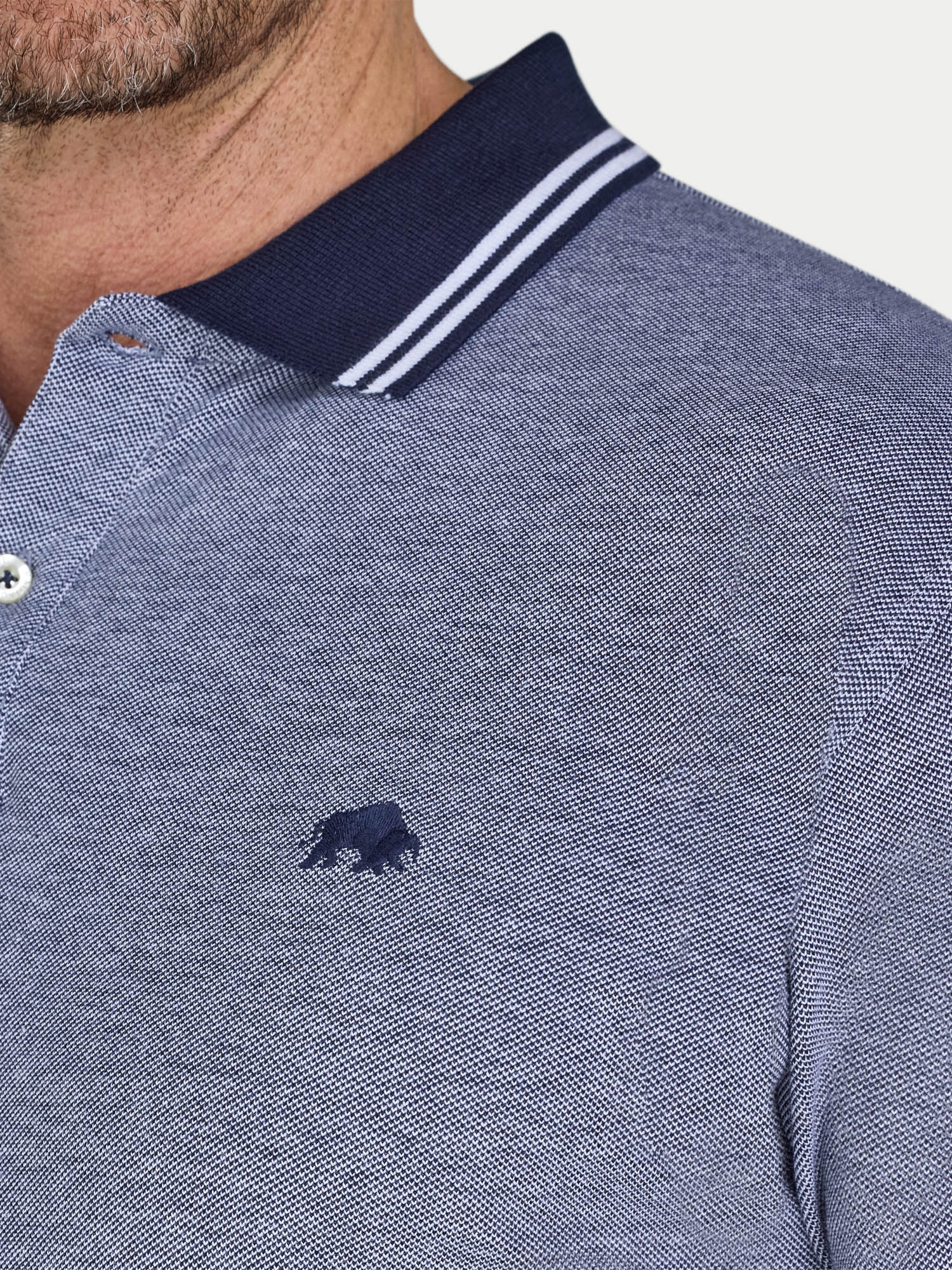 Close-up of a blue polo shirt with a logo on a white background