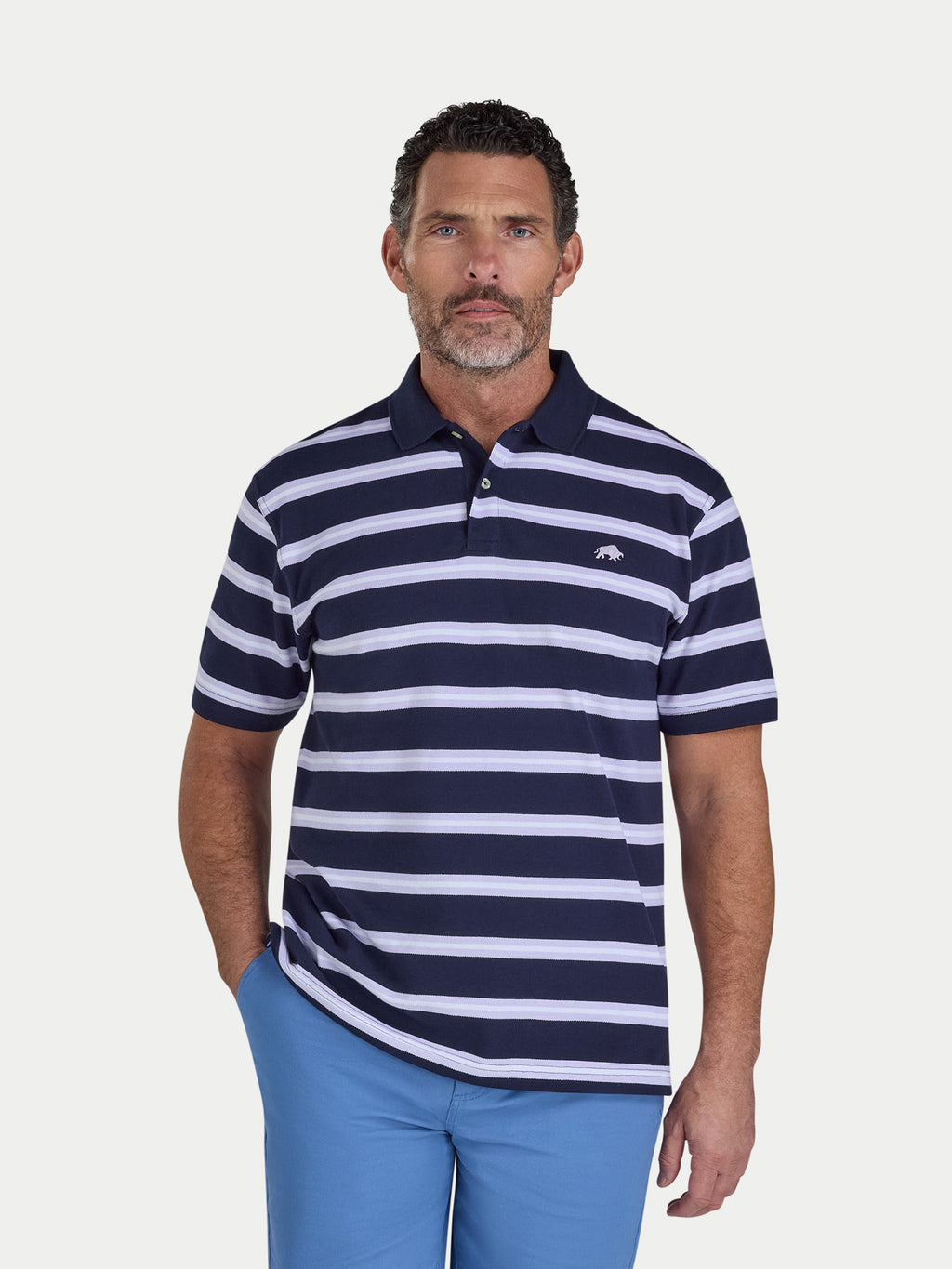 Man wearing a navy and white striped polo shirt with blue pants on a light gray background
