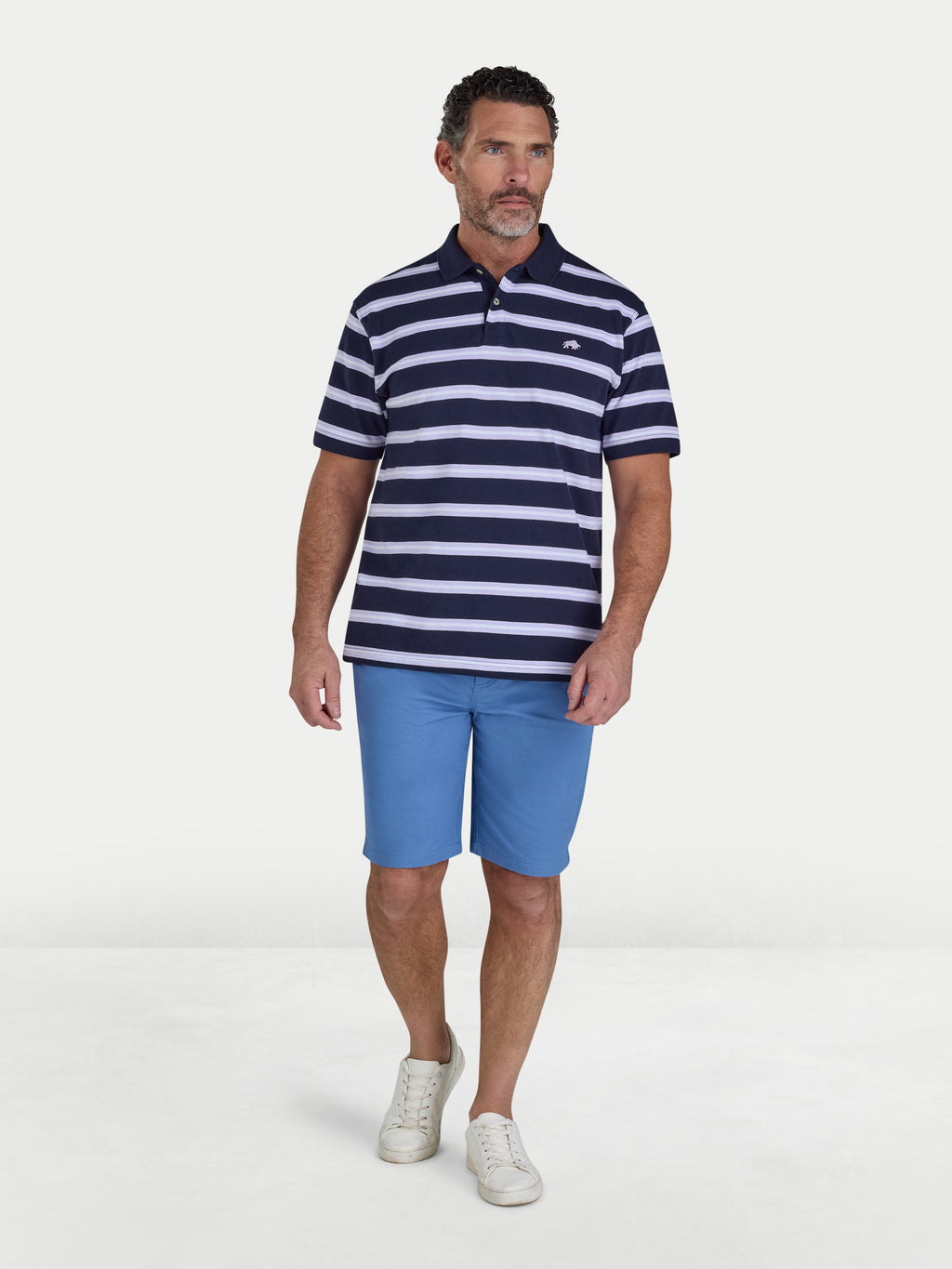 Man wearing a navy and white striped polo shirt and blue shorts on a white background