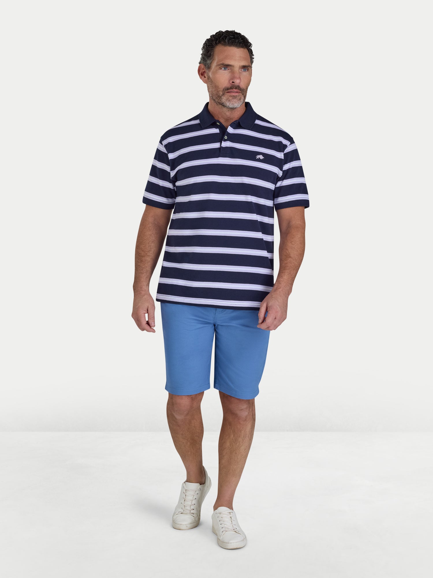 Man wearing a navy and white striped polo shirt and blue shorts on a white background