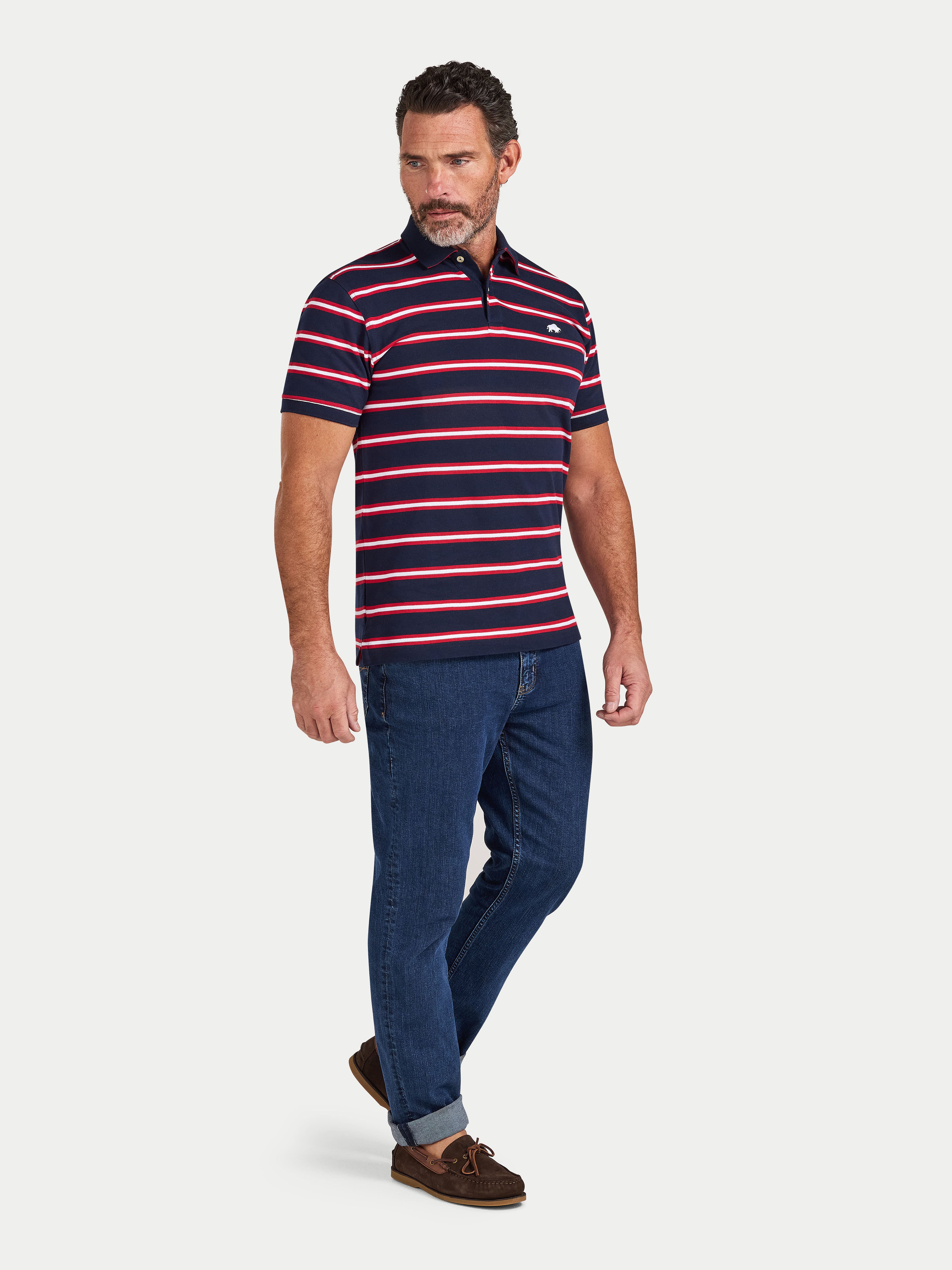Man wearing a striped polo shirt and jeans on a white background