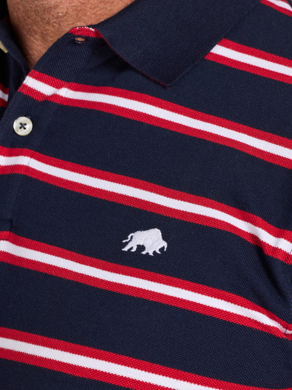 Navy blue polo shirt with red and white stripes and a logo on the chest.