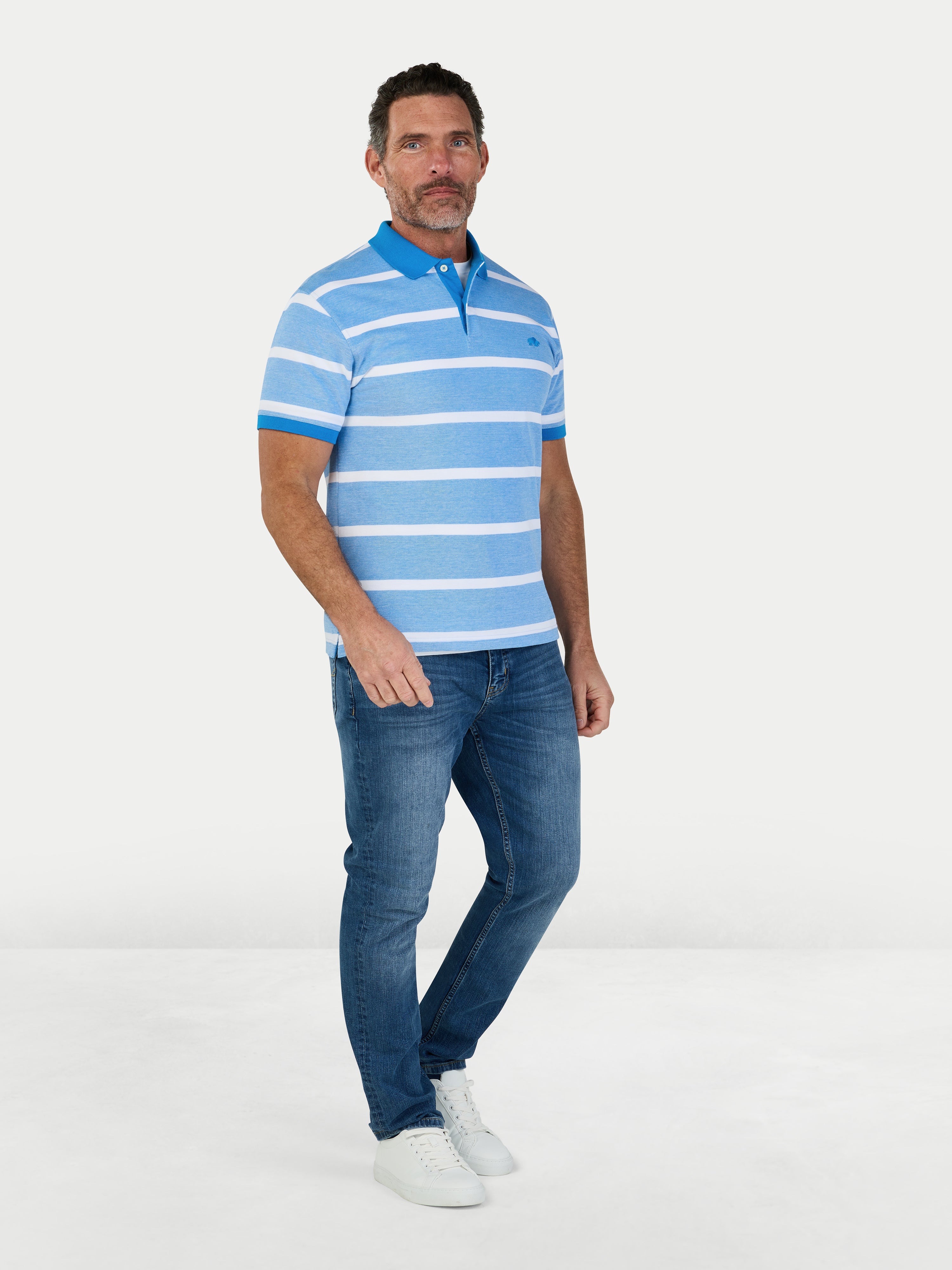 Man wearing a blue and white striped polo shirt and jeans on a white background