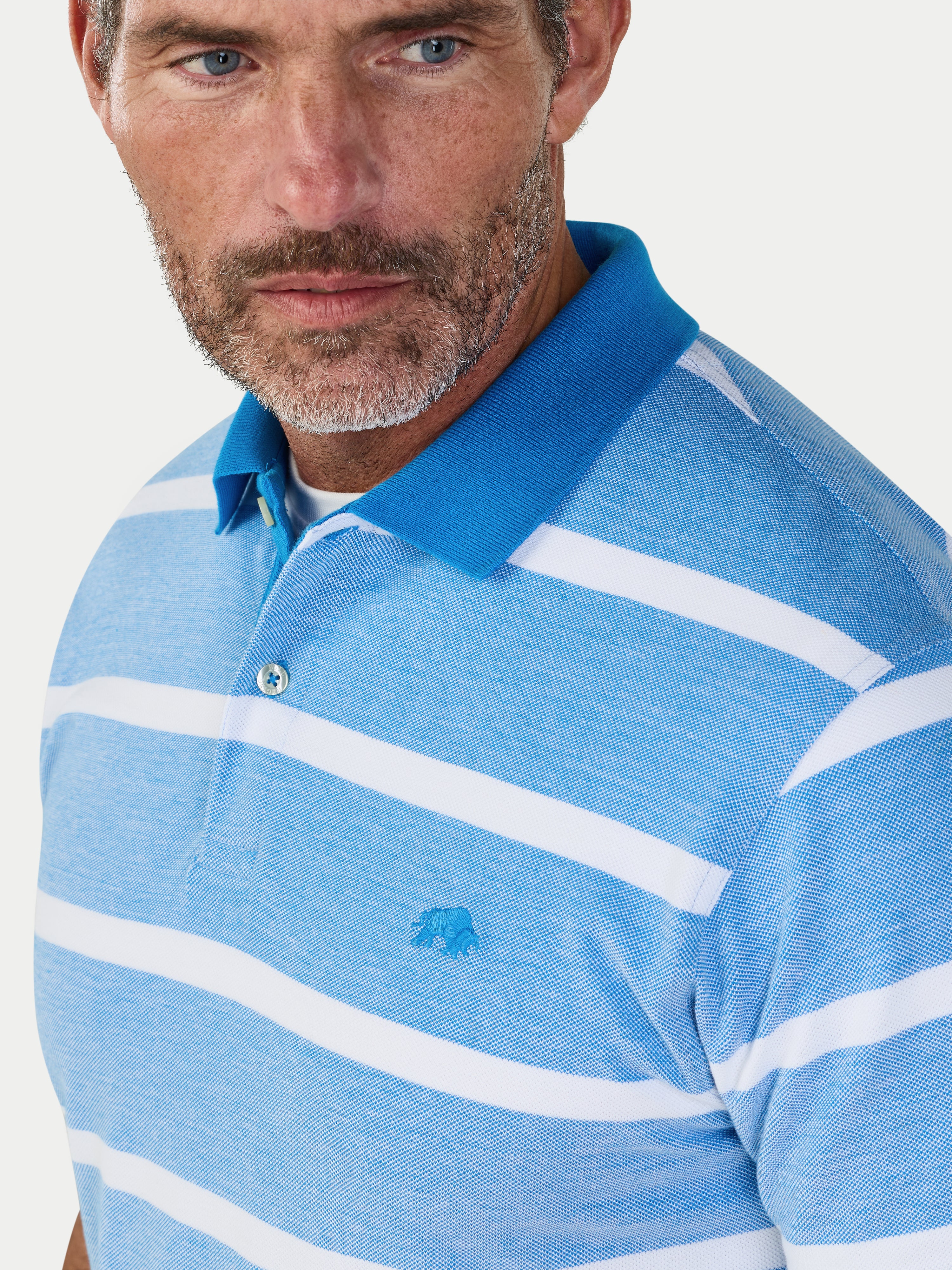 Man wearing a blue and white striped polo shirt with a small Raging Bull logo on a light gray background