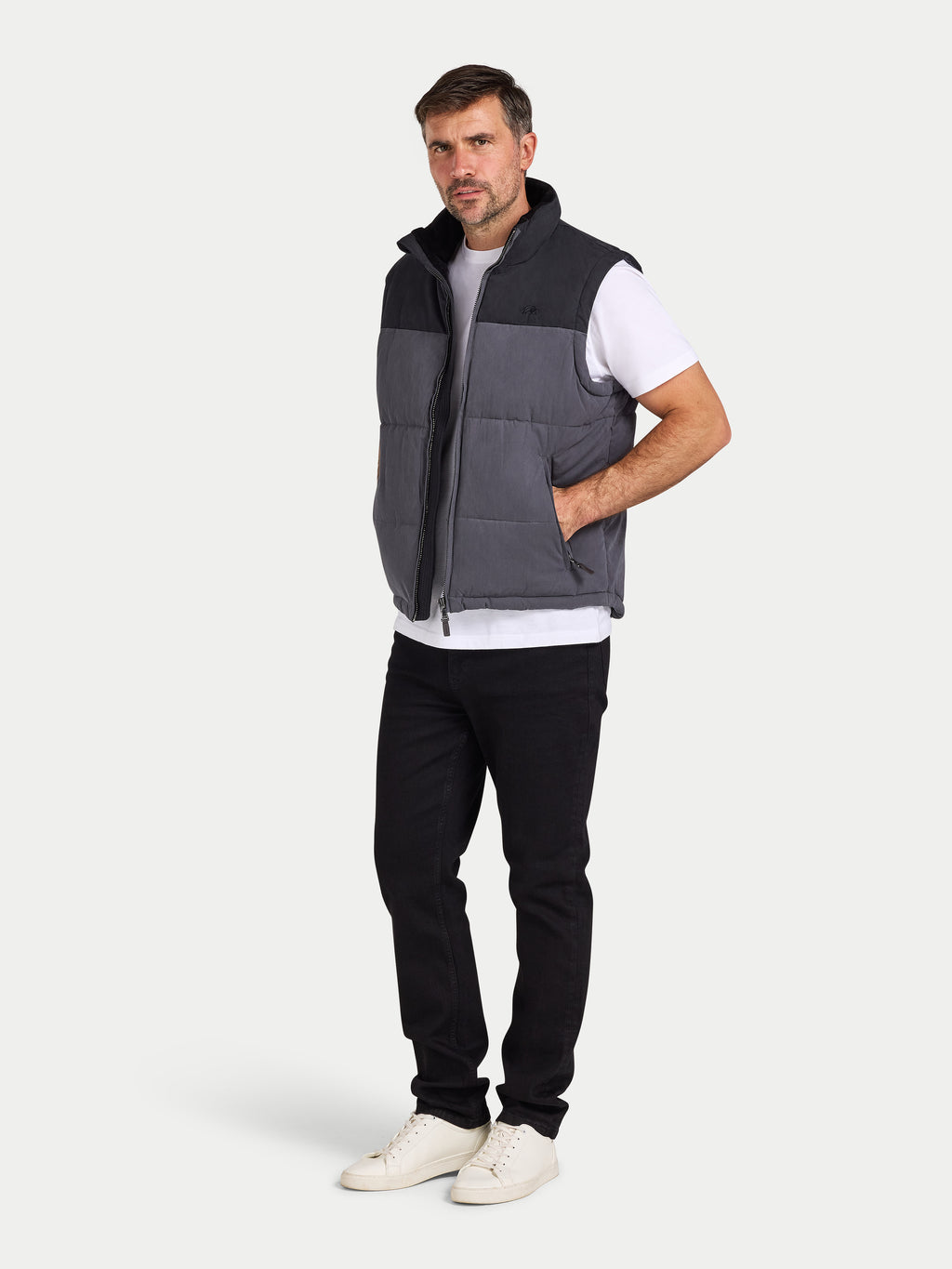 Man wearing a gray and black quilted vest on a white background