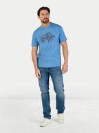 Man wearing a blue t-shirt with a graphic design and jeans on a white background