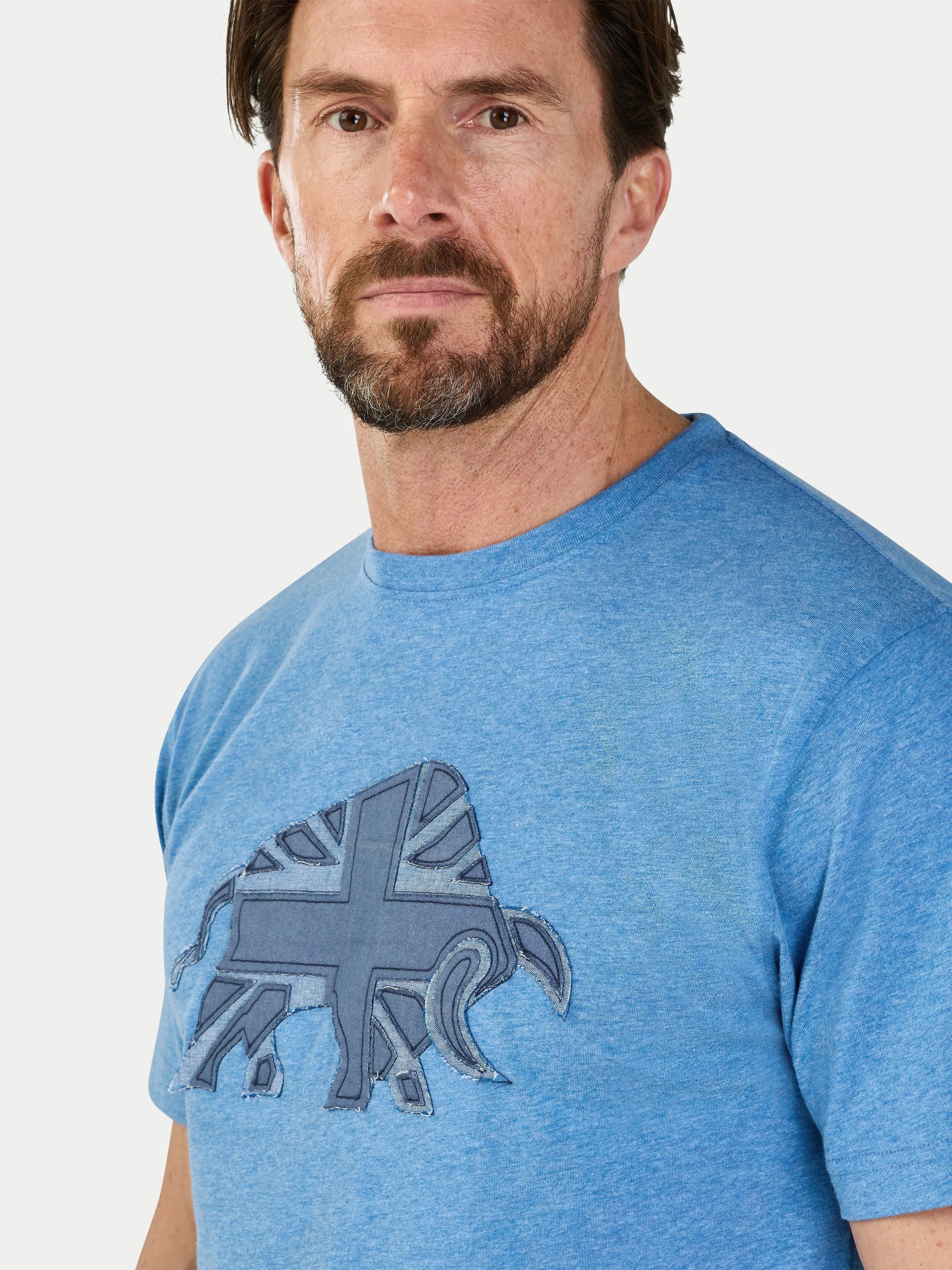 Man wearing a blue t-shirt with a graphic design on a light gray background