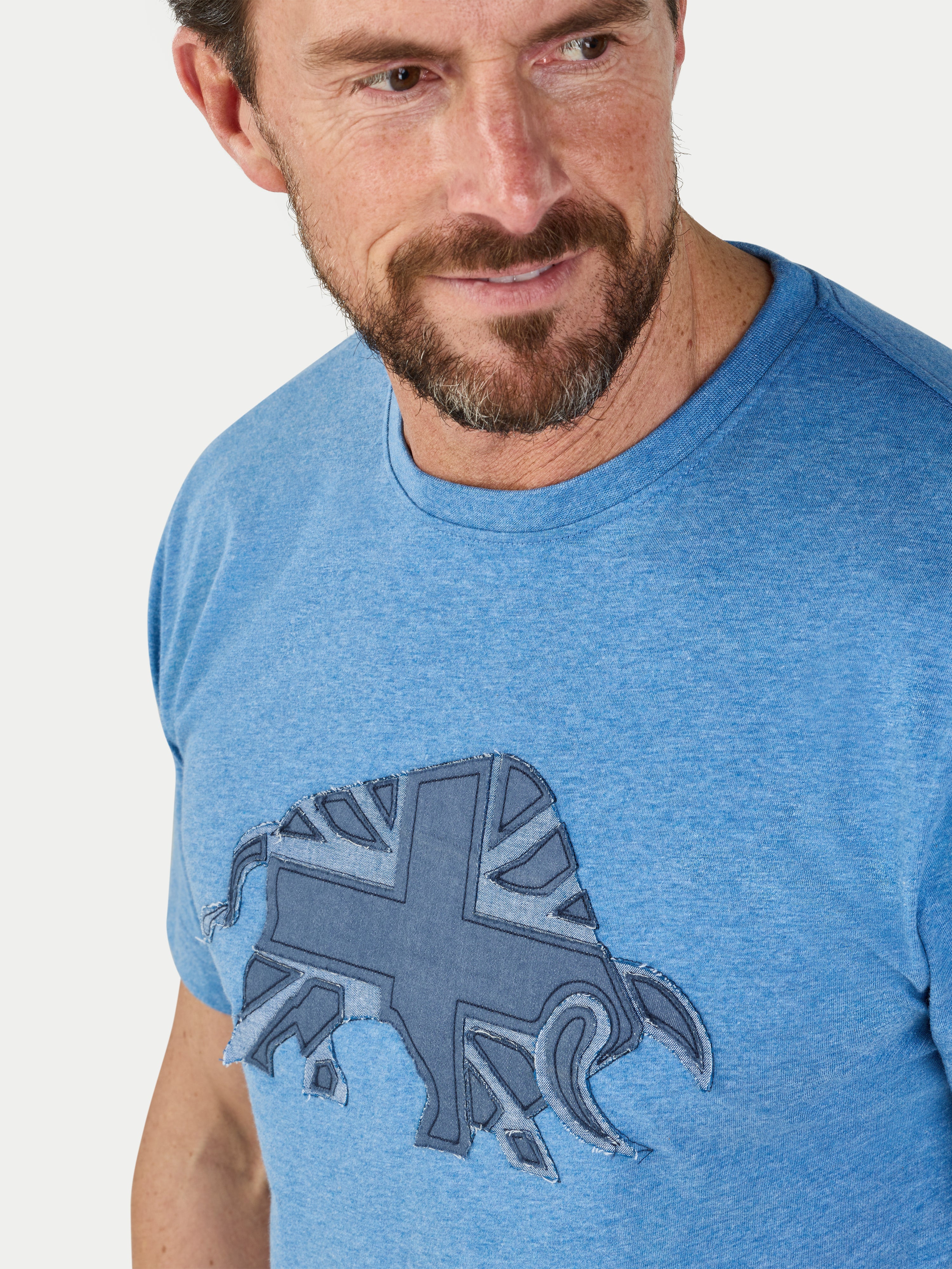 Man wearing a blue t-shirt with a graphic design on a plain background