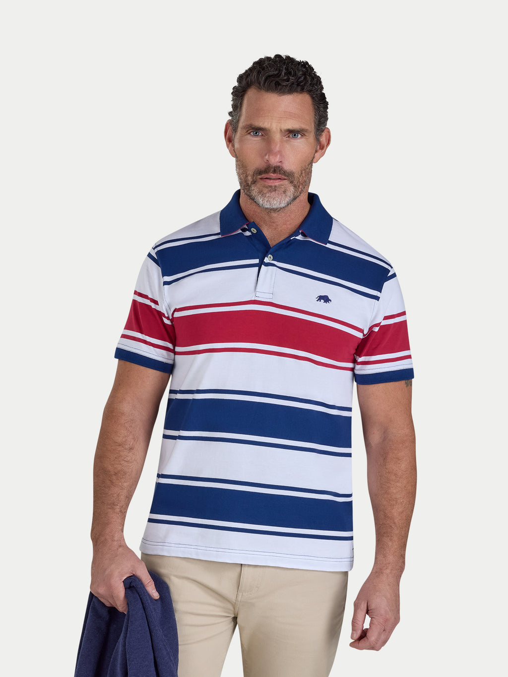 Man wearing a striped polo shirt with a visible brand logo on a plain background