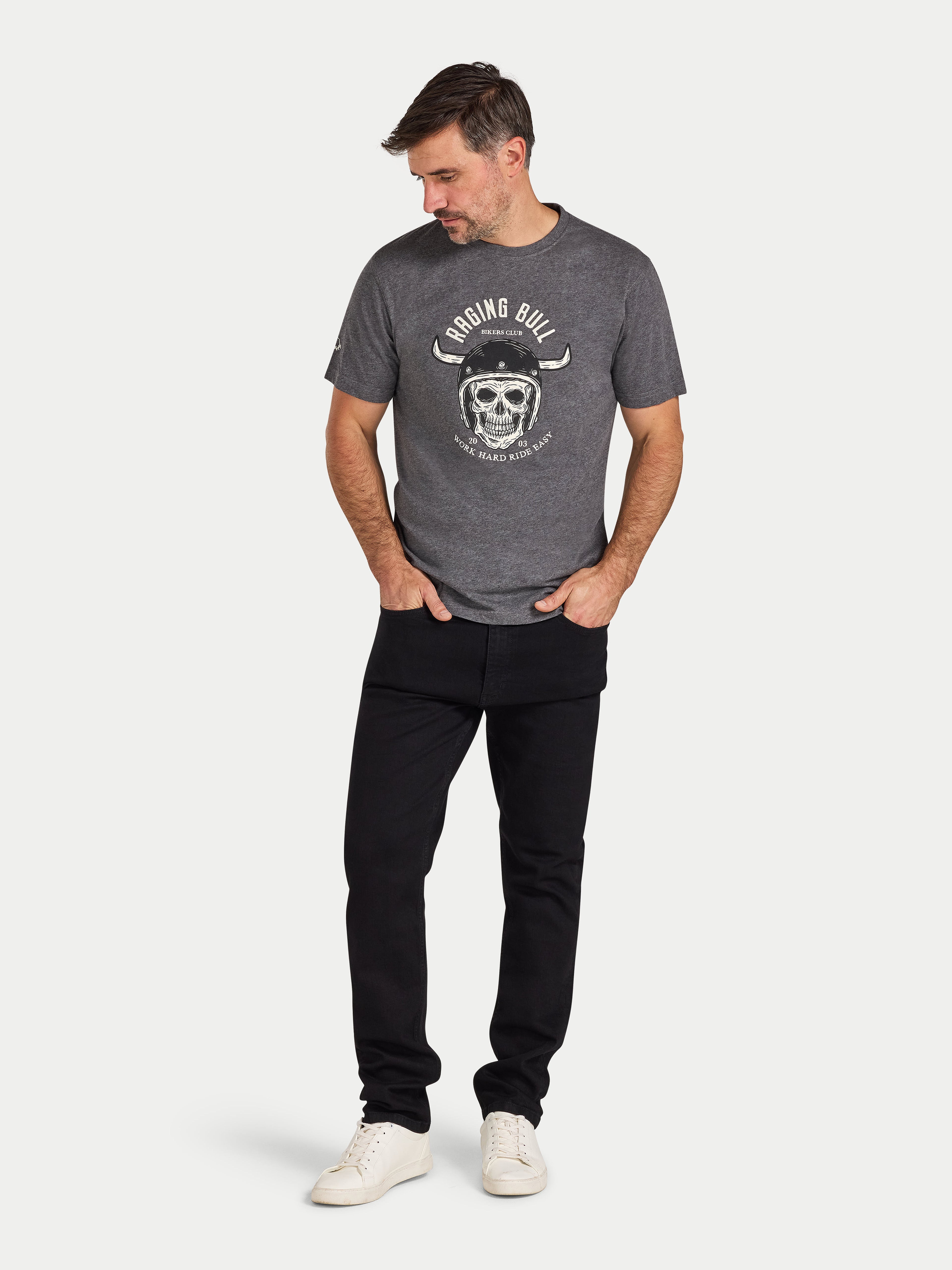 Man wearing a gray t-shirt with a graphic design and black pants on a white background